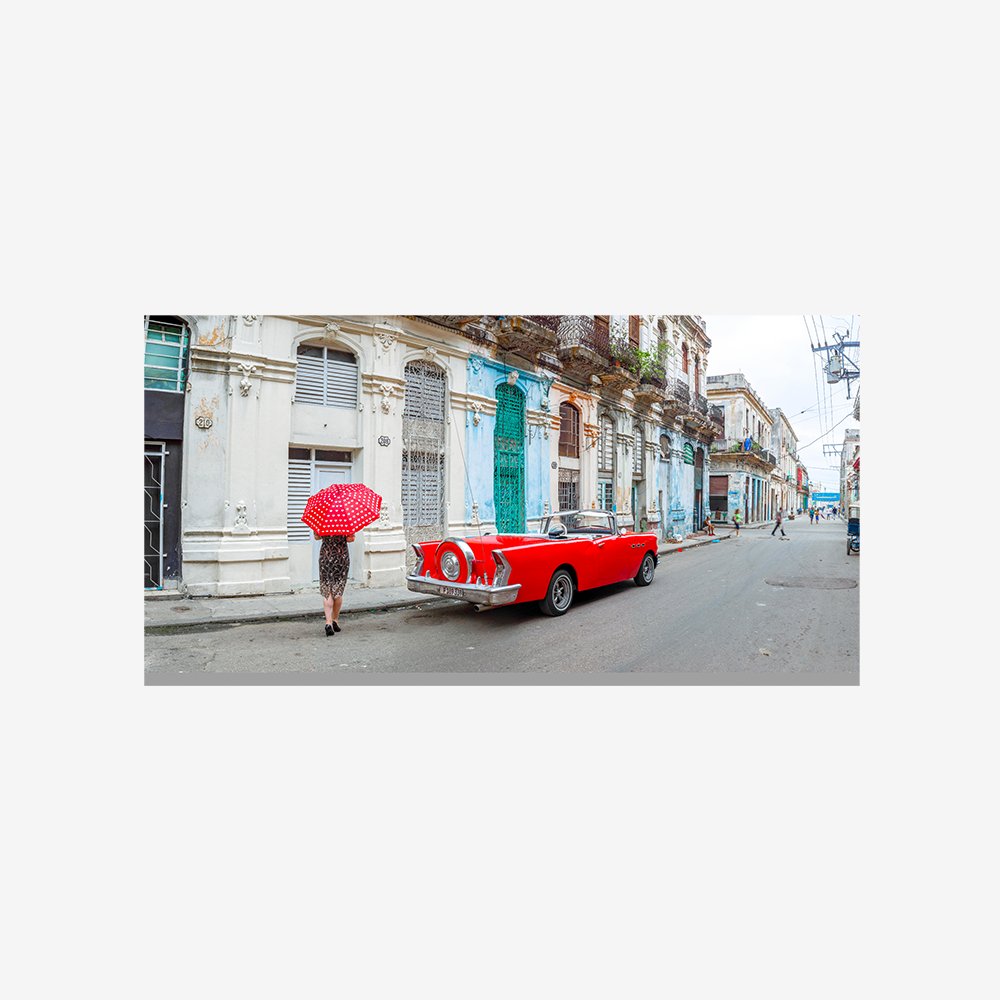 Woman with red umbrella by a vintage car on the street of Havana, Cuba, FTBR 1851